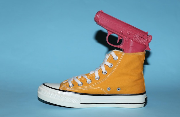 Yellow sneaker with gun on blue background Minimalism Concept art