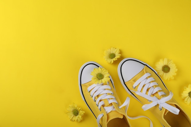 Yellow sneakers with flowers on yellow background