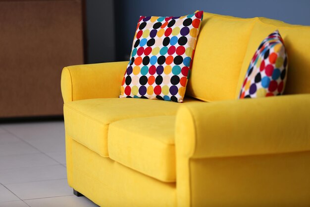 Yellow sofa and multicoloured pillows on a blue wall background