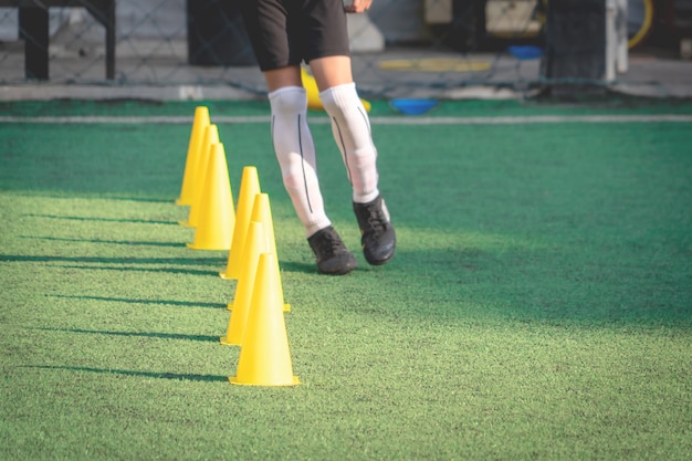 Foto indicatore giallo dei coni di addestramento di sport sul campo di erba verde di calcio per la sessione di allenamento di calcio dei bambini