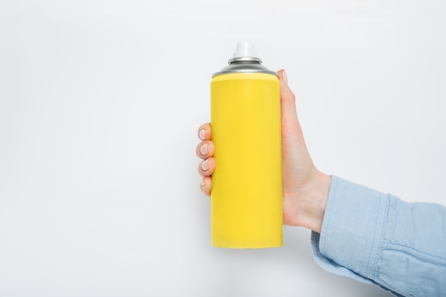 Yellow spray can for spraying in a female hand. 