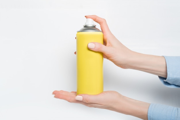 Yellow spray can for spraying in a female hands. 