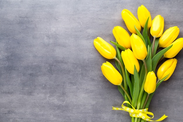 Yellow spring flowers, tulip on a gray surface.