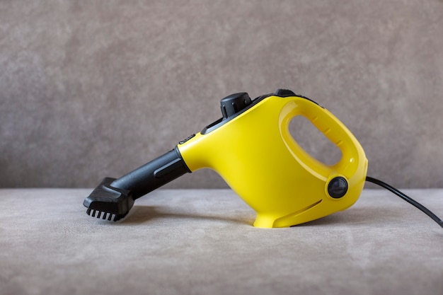 Yellow steam cleaner with brush stands on brown sofa