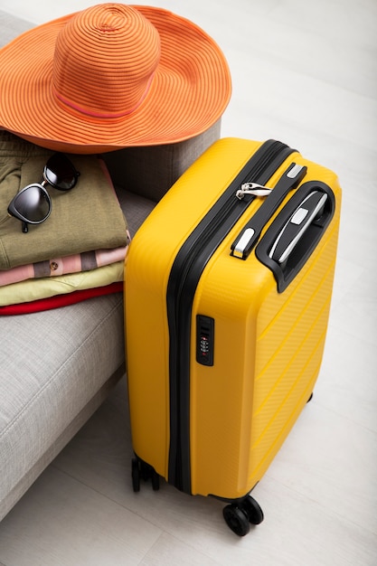服を持って旅行するために詰められた黄色のスーツケース