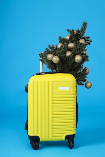 A yellow suitcase with a decorated christmas tree