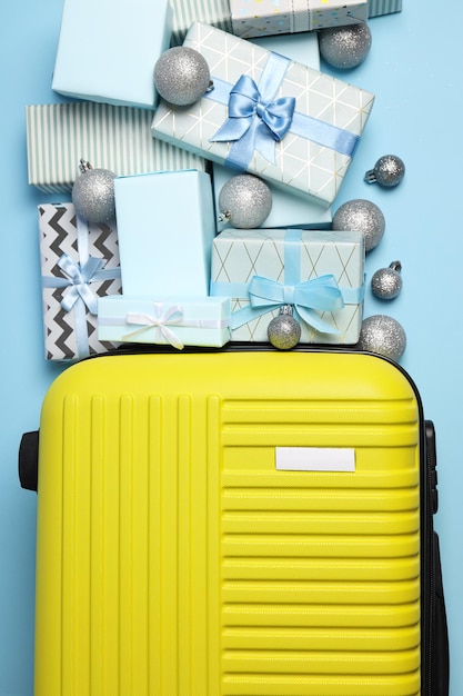 Yellow suitcase with gifts on a blue background