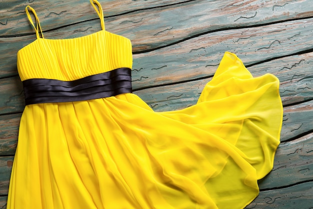 Yellow summer dress. Casual dress with black insert. Lady&#39;s garment on green shelf. Clothing item for young girls.