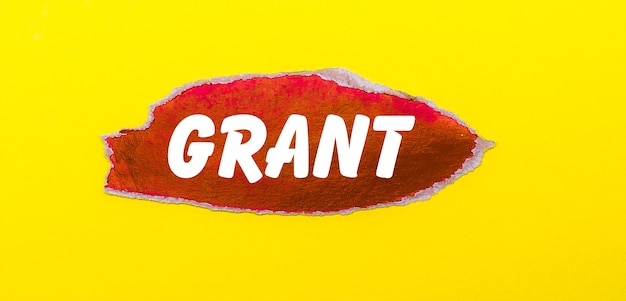 Photo on a yellow surface, a sheet of red paper with the word grant