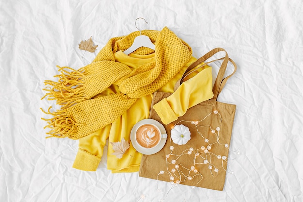 Yellow sweater with knitted scarf,  tote bag and cocoa drink. Autumn mood. Fashion clothes collage on white background. Top view flat lay.