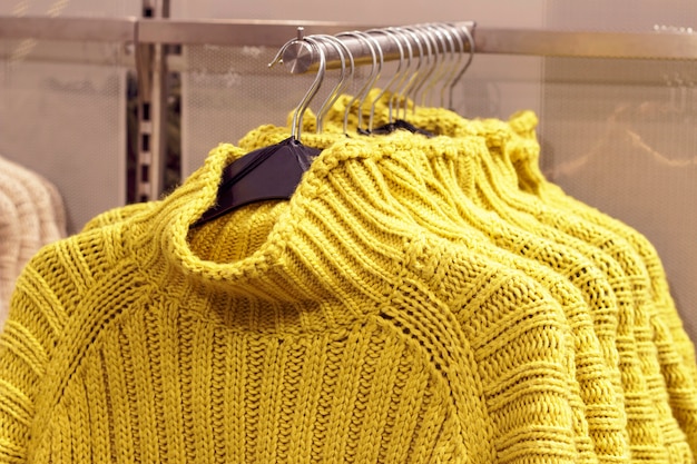 Yellow sweaters hanging on hangers in store, concept of clothing purchase