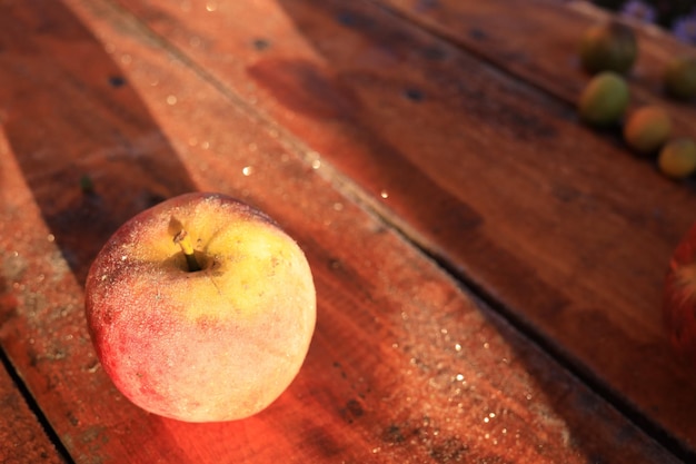일출 때 마당에 있는 나무 탁자에 있는 노란색 달콤한 사과 과일의 그늘