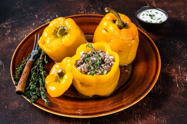 Yellow sweet bell pepper stuffed with meat, rice and vegetables. Dark background. Top view.