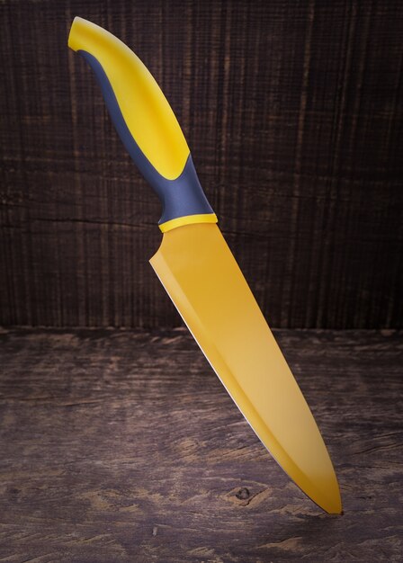 Yellow table knife stuck in the wood texture.