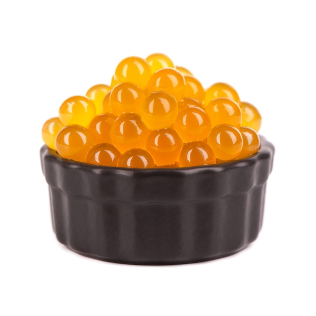 Yellow tapioca pearls for bubble tea isolated on white background. Tapioca pearls in black ceramic bowl.