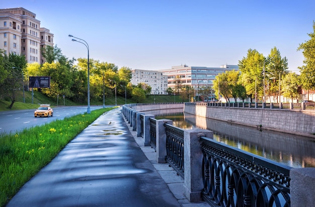 Yellow taxi on the embankment in the morning light Yauza river Moscow