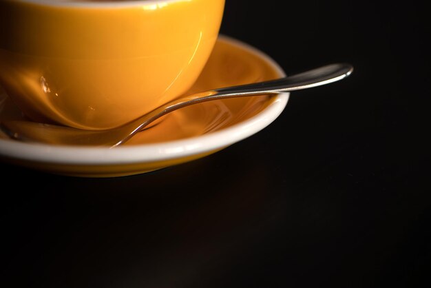 暗い背景に黄茶またはコーヒーカップとプレート