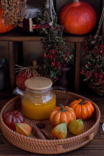 yellow tea with sea buckthorn berries in a glass teapot Decorated with physalis and autumn pumpkins dried herbs for winter in the background