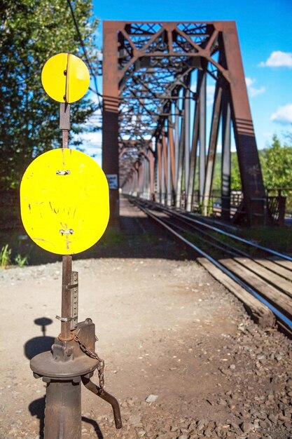 Photo yellow telephone pole by railroad track against sky