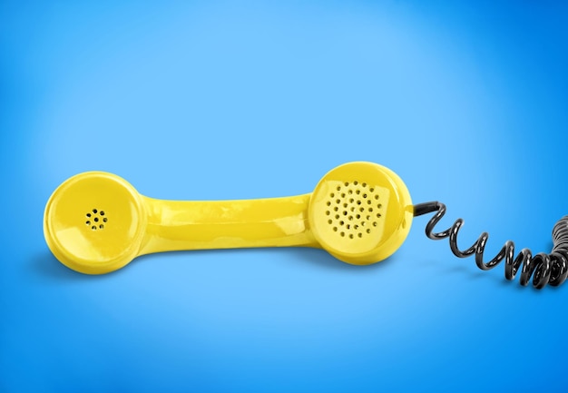 Yellow telephone retro receiver on a blue background. Communication and technology