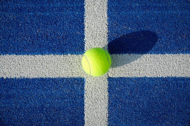 Желтый теннисный мяч на корте на голубой траве - теннисовый мяч на корт на синей траве