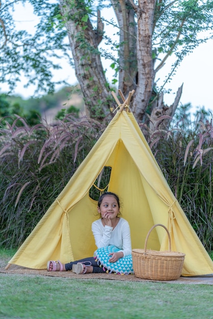 Tenda gialla con bambina carina dentro nella natura