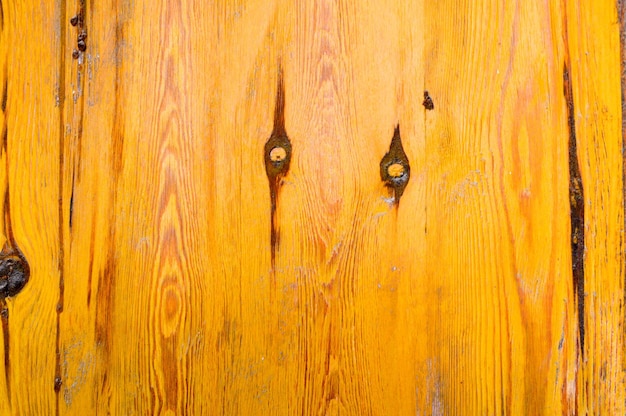 The yellow texture of an old ancient wooden wall covered with lacquer with brown veins fibers and knots The background