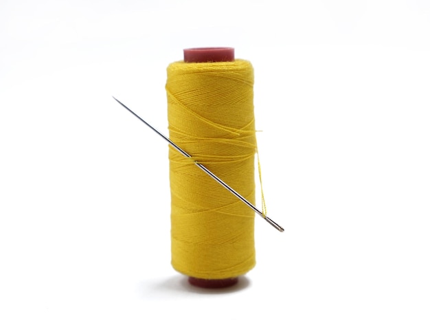 Photo yellow thread and needle over white background