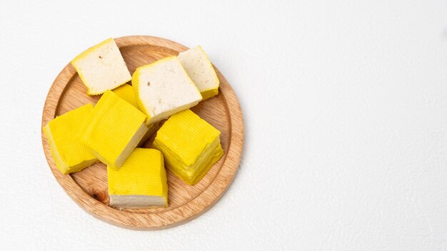 Photo yellow tofu on wooden cutting board isolated on white background