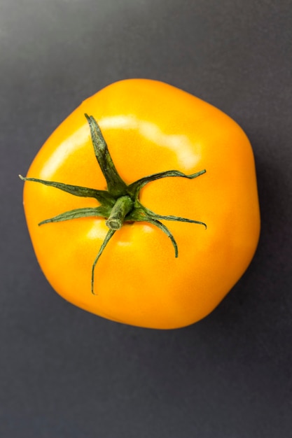 Yellow tomato on black. Top view