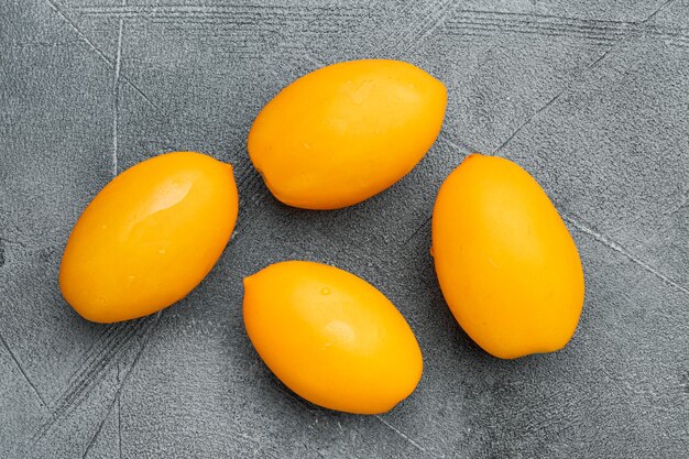 Yellow tomato set, on gray stone table background, top view flat lay