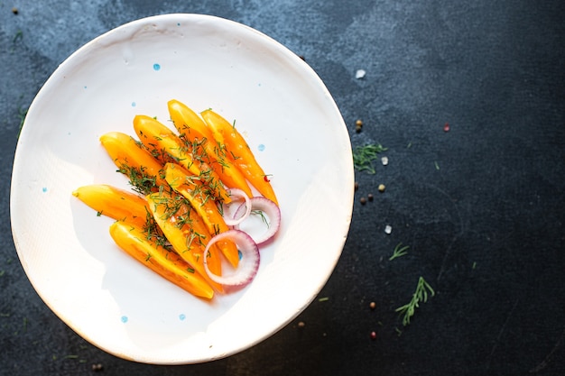 Yellow tomatoes with onion rings on a plate