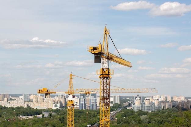 Yellow tower cranes at the construction site at the multi storey houses background