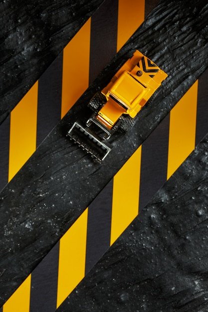 Yellow toy bulldozer. Black and yellow fence tape