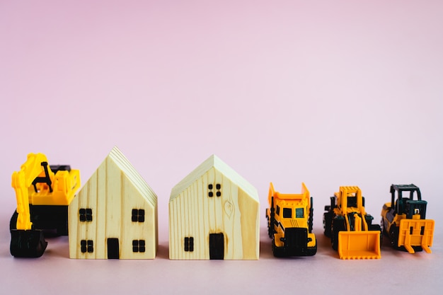 A yellow toy heavy machinery with wooden house model