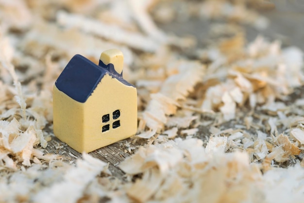 Yellow toy house on wooden surface with sawdust