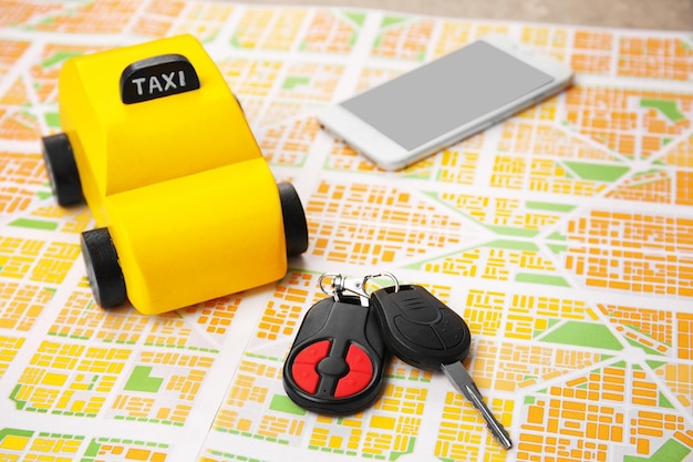 Yellow toy taxi car key and phone on map