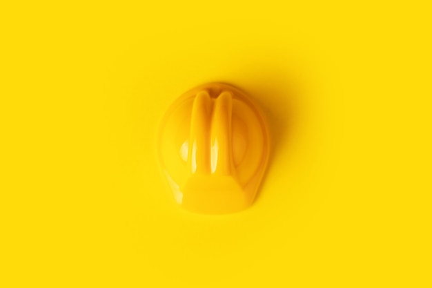 Фото Желтый игрушечный рабочий шлем на желтом фоне, концепция строительства минимализма