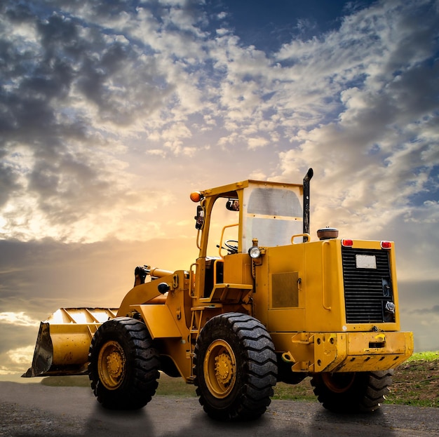 Photo yellow tractor on the road with cloudy blue sky