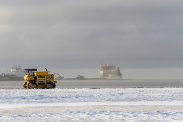 Yellow tractor in winter tundra. The road construction.