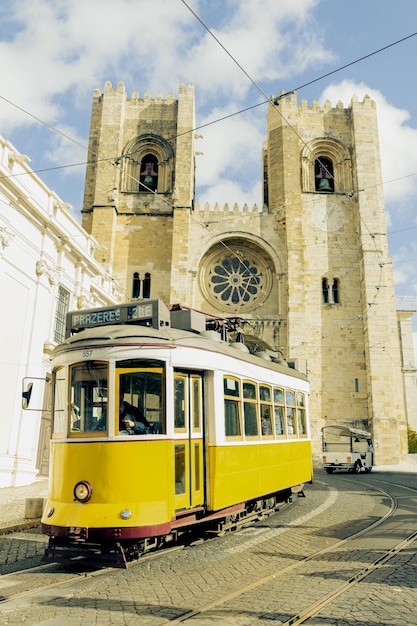 Yellow tram next to the cathedral of Lisbon Portugal