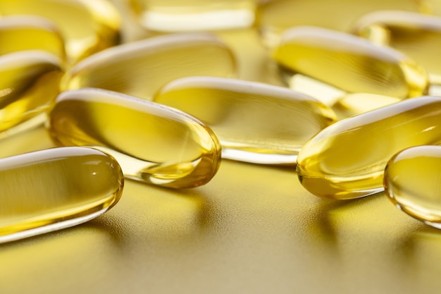 Yellow transparent fish oil capsules on gray surface