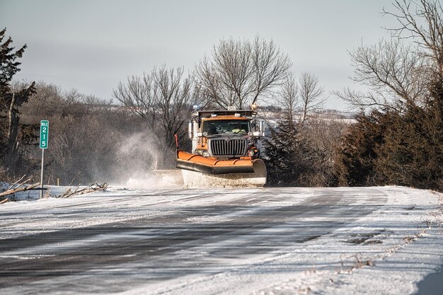 Foto camion giallo che spazza la neve sulla strada foto