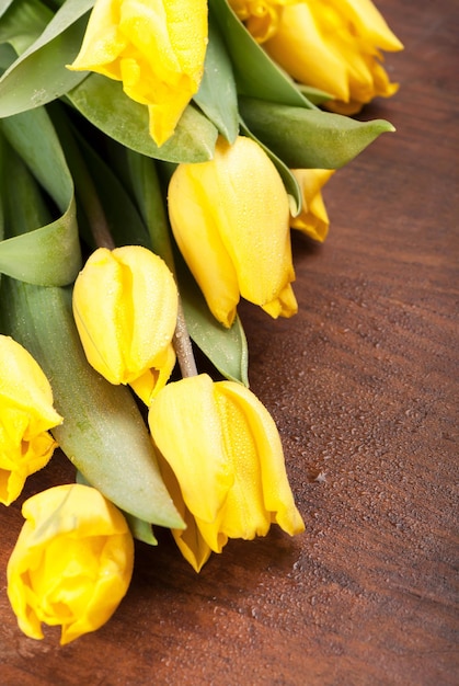 Fiori di primavera luminosi tulipani gialli su sfondo di legno