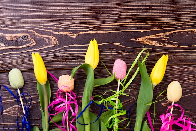 Yellow tulips and candies. Sweets and flowers on wood. Delicious and colorful gift. Show your care.