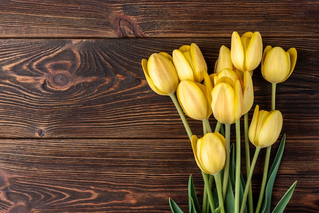 Yellow tulips on dark wooden table.