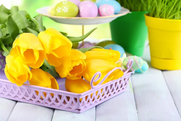 Yellow tulips and Easter eggs on table on natural background