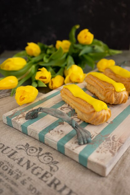 Tulipani gialli ed eclair sul vassoio in legno d'epoca