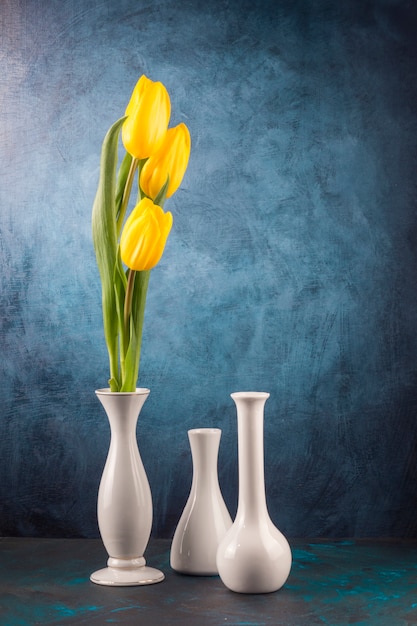 Yellow tulips and empty vases on table