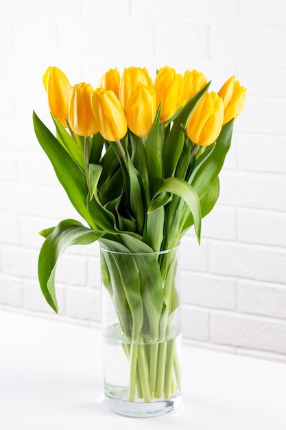 明るい背景の上の黄色いチューリップの花の花束バレンタインデー母の日と誕生日のお祝いのコンセプト